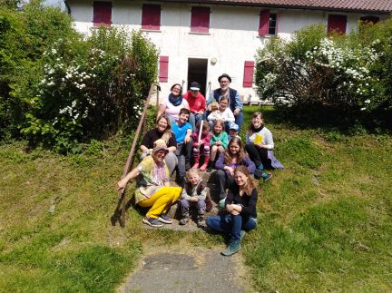 Gruppenfoto mit etwa 15 Menschen auf einer Treppe vor dem Haus. 5 Erwachsene und 10 Kinder